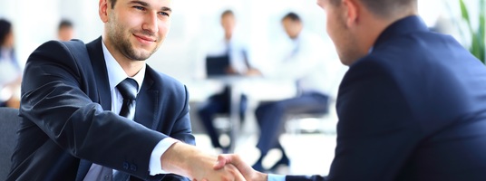 Zwei Geschäftskollegen schütteln die Hände bei einer Besprechung.